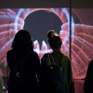 Two women look at a videoprojection that depicts the graphical visualization of an earthquake.