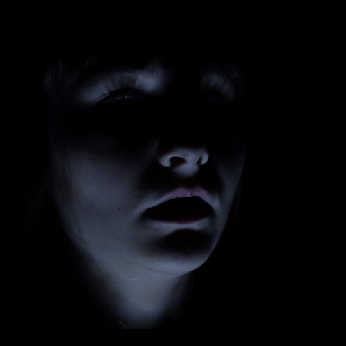 The face of a young woman in the dark.